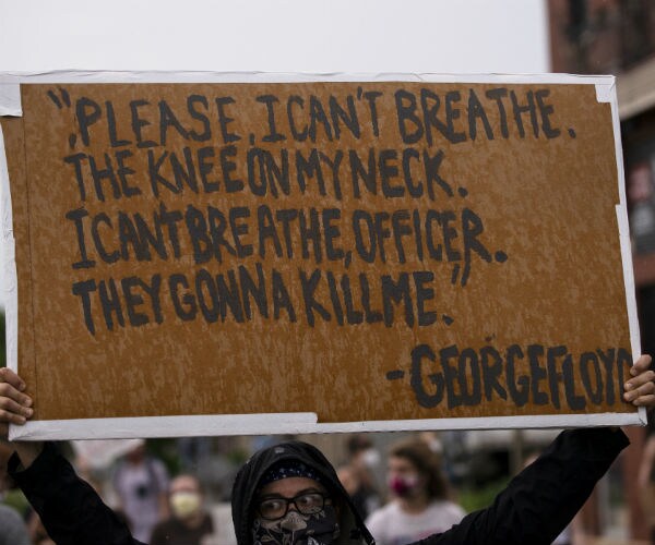 a man holds a sign reading: "please, i can't breathe. the knee on my neck. i can't breathe, officer. they gonna kill me