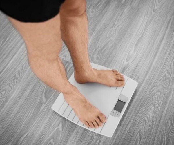 man weighing himself on scale