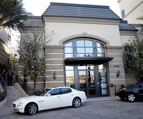 a high end car is parked in front of an upscale apartment building