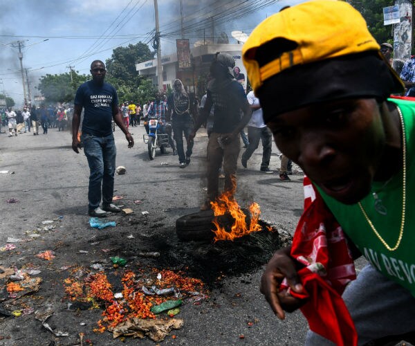 protesters march in the street as a tire burns