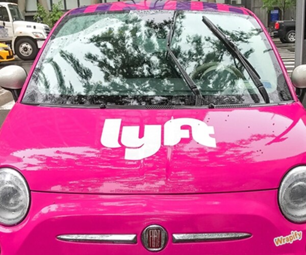 Fiat 500 painted pink and carrying a Lyft logo is parked in the streets of Manhattan