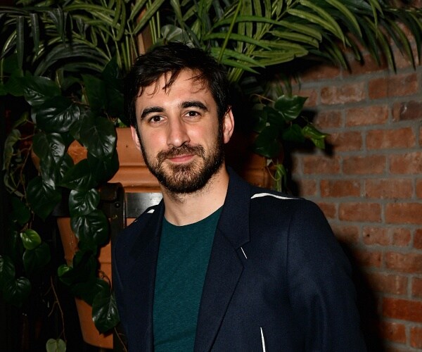 ferdinand kingsley stands in front of brick wall