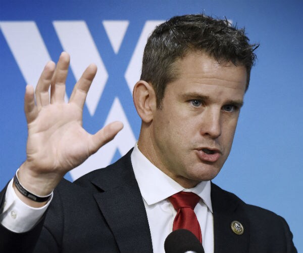 adam kinzinger holds up the five fingers of his right hand like a bear claw during a news conference