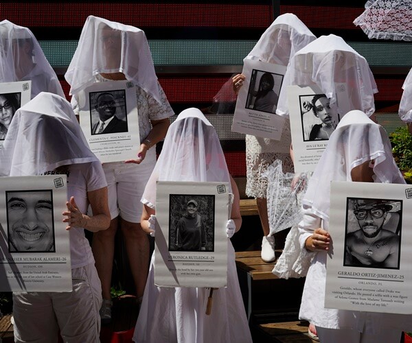 gun violence protesters have sheets over their heads and hold images of victims of gun violence