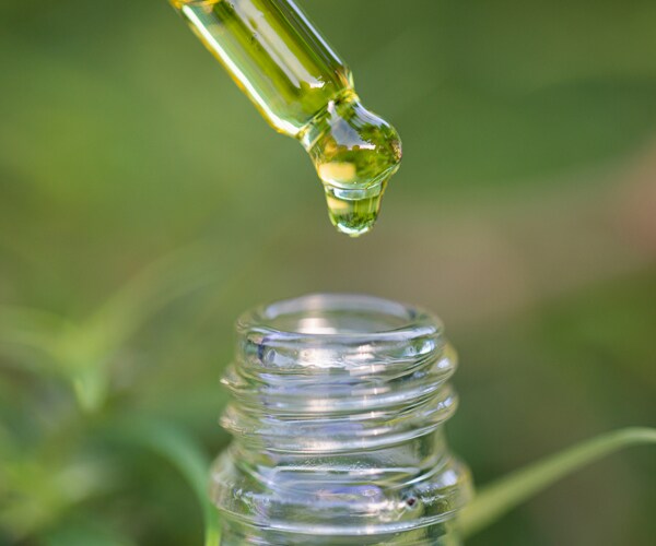 a drop of cbd oil over a glass bottle
