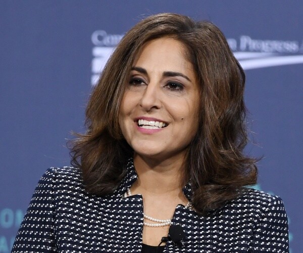 tanden in a blue and white coat and black top with a pearl necklace