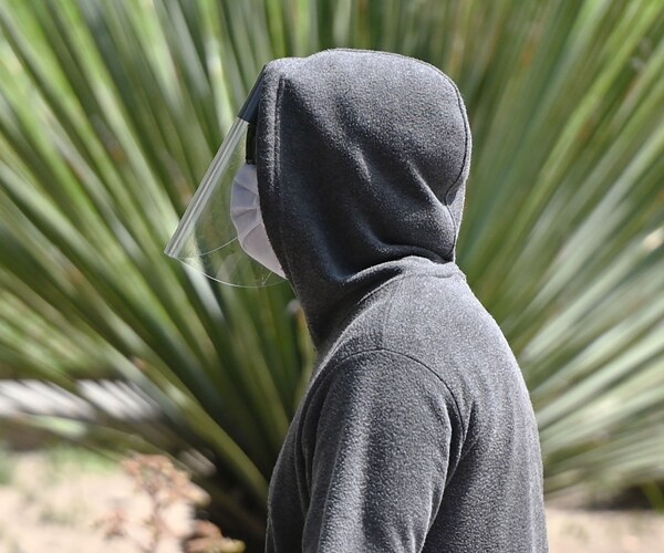 a man walking while wearing a face mask and face shield