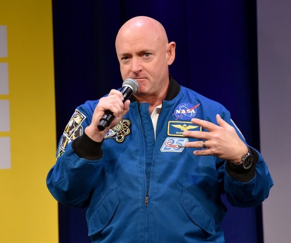 kelly in blue astronaut's uniform speaking into a mic