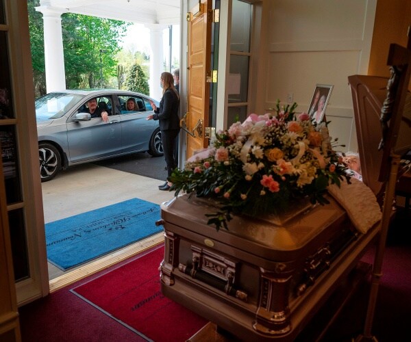 casket is shown with flowers in a funeral home with a car driving by