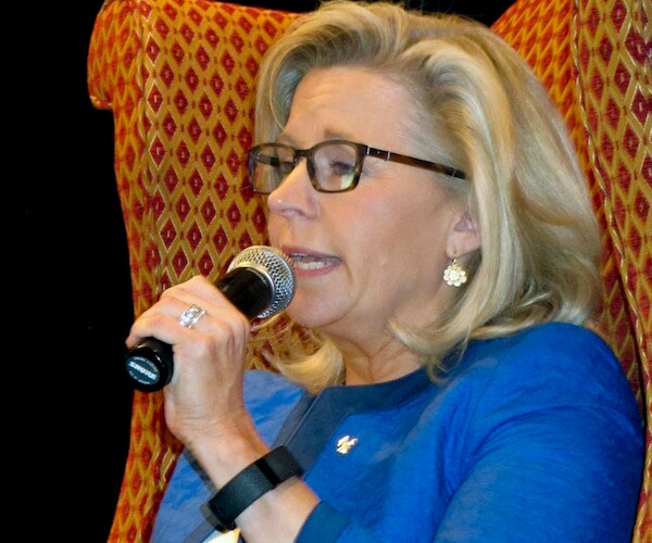wyoming republican representative liz cheney sits and speaks into a microphone while on stage during a conference