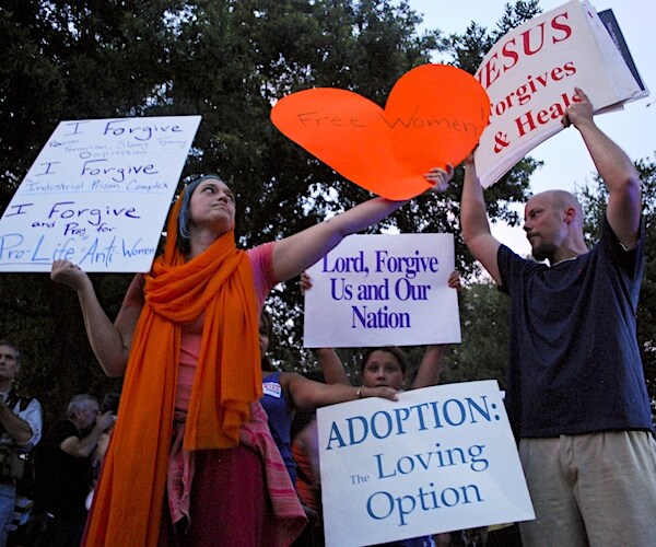 a pro choice rally crowd chants and holds up signs supporting unborn children
