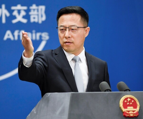 Zhao Lijian gestures with his hand while speaking at a press conference