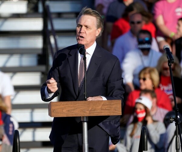 david perdue stands behind podium