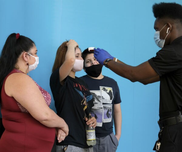 a young black man, dress in all black, check the temperature of a woman at the garden state plaza mall in new jersey