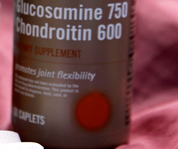 a bottle of glucosamine and white pills lay on a table