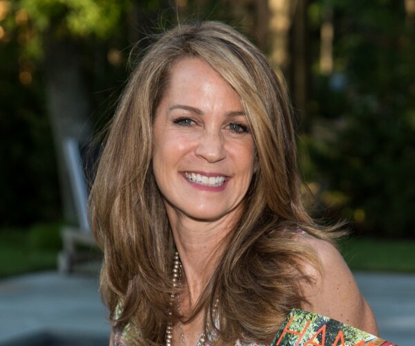 sandler smiling while wearing a patterned dress and holding a magazine