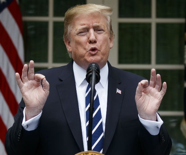 president donald trump gestures with his hands as he speaks to reporters