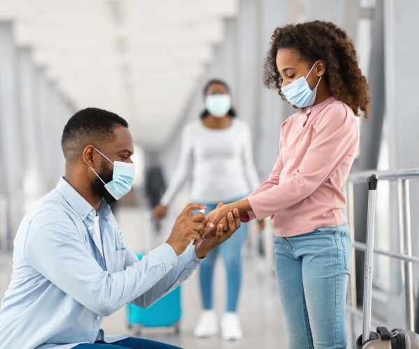 family at airport, Dad using hand sanitizer to clean daughter's hands