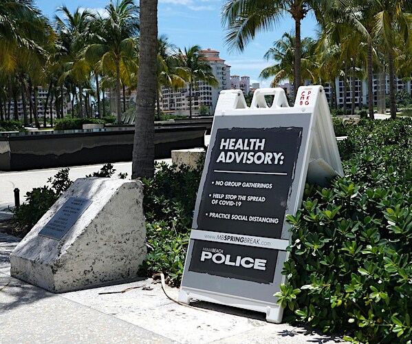a police sign warns of south pointe park on miami beach closed due to the coronavirus