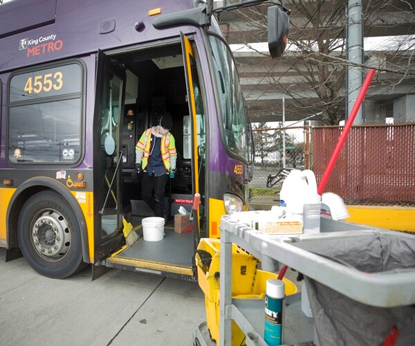 man in protective gear cleans a bus in seattle
