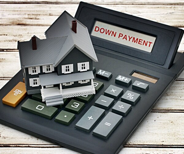 calculating down payment, model house on a calculator with words down payment over a distressed wood background 

