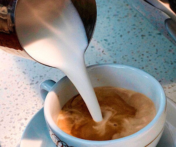 cream is poured into a a coffee cup on a table