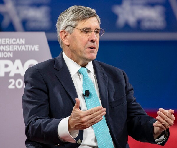 stephen moore sits on stage against a cpac backdrop