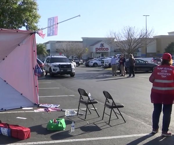 tent lying on its side in parking lot with person standing next to it