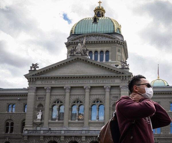 a pedestrian in front of the swiss house of parliament in bern