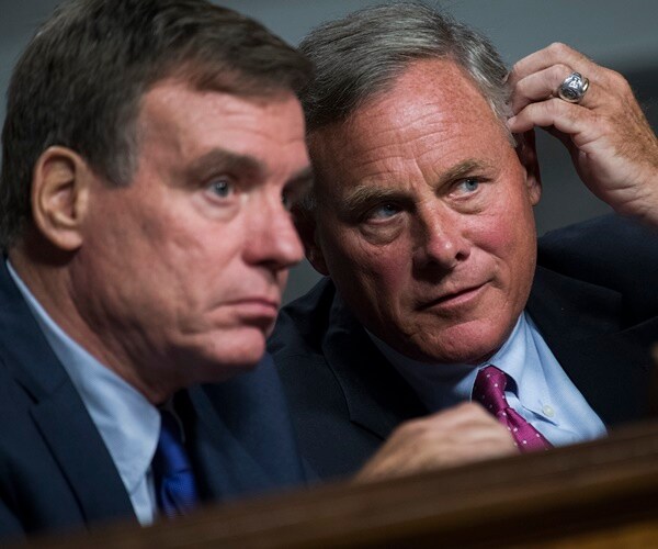 sens. warner and burr speak with their heads close to each other