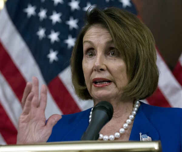 house speaker nancy pelosi gestures with her right hand as she speaks to the media wearing a blue suit, white pearls