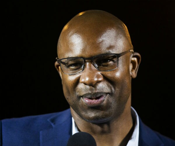 a smiling jamaal bowman is seen wearing glasses and in a blue dress jacket and white dress shirt