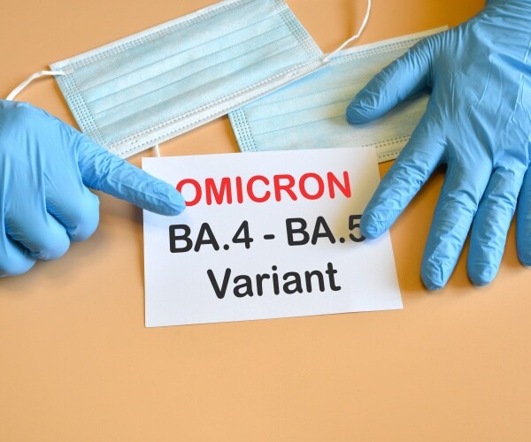 hands with blue surgical gloves pointing to sign saying Omicron BA.5, BA.5 Variant