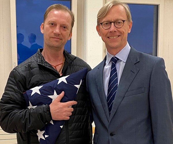 michael white poses with brian hook and a folded flag