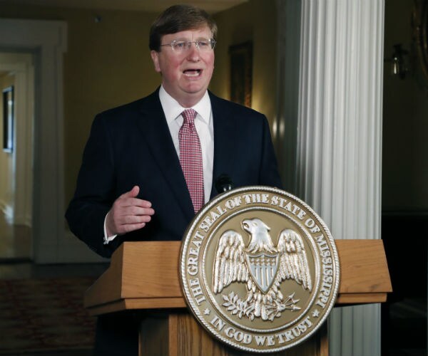 tate reeves speaks at a podium with the mississippi state seal on the front
