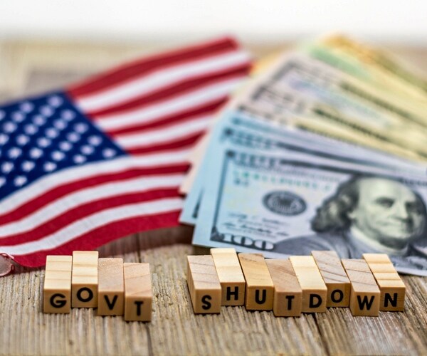 government shutdown usa concept with american flag and money bills on white background and wooden board.

