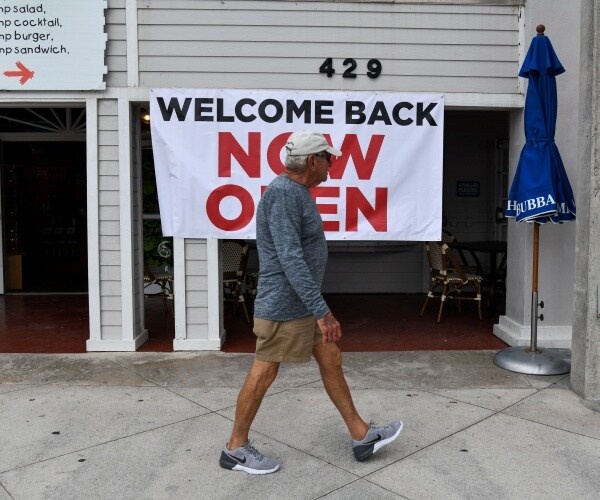 welcome back now open sign in front of a business