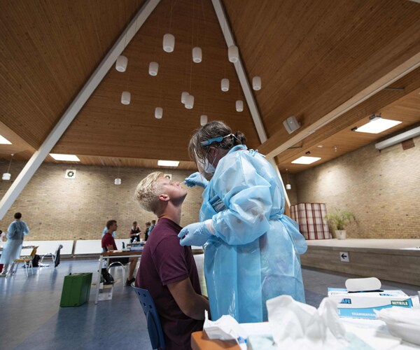 a healthcare worker in the netherlands performs a covid-19 test on a patient