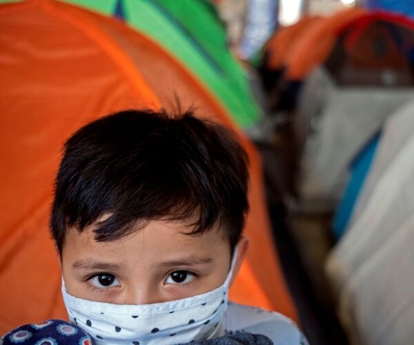 child migrant shown in a migrant camp with tents