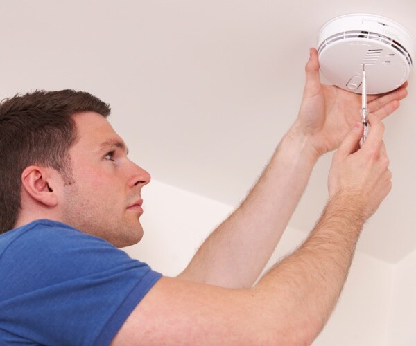 man installing home carbon monoxide detector on ceiling 