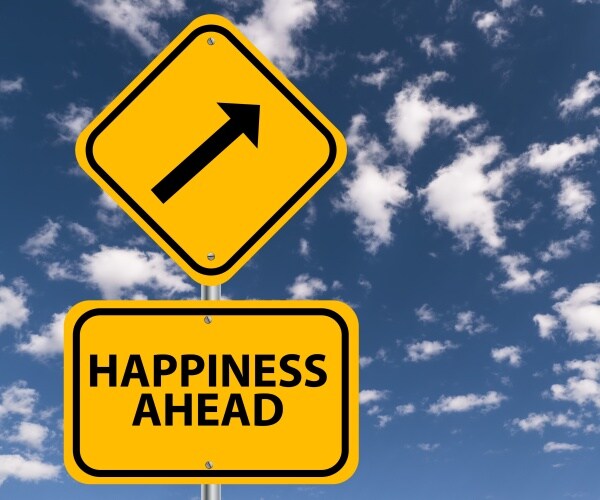 yellow road sign with blue sky behind it saying "happiness ahead"