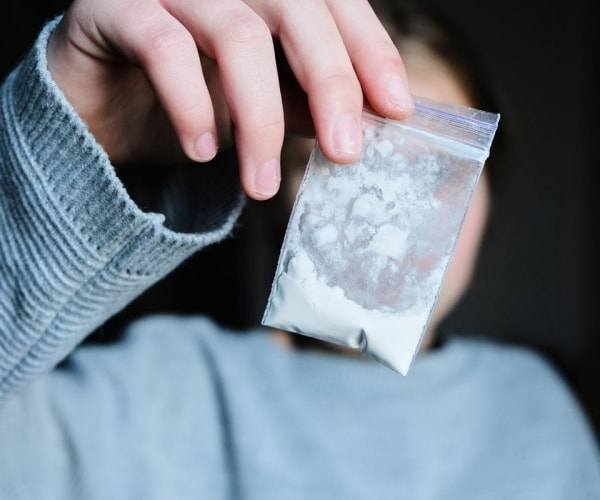 young adult holding up a bag of meth