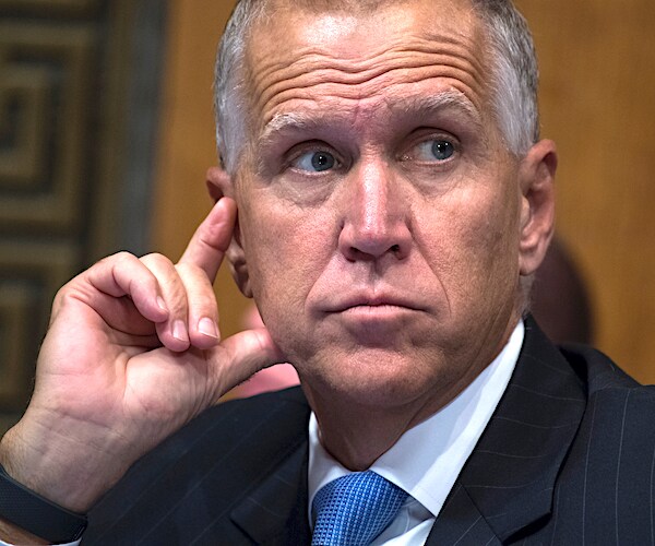 thom tillis puts his right index finger to his ear during a senate committee hearing