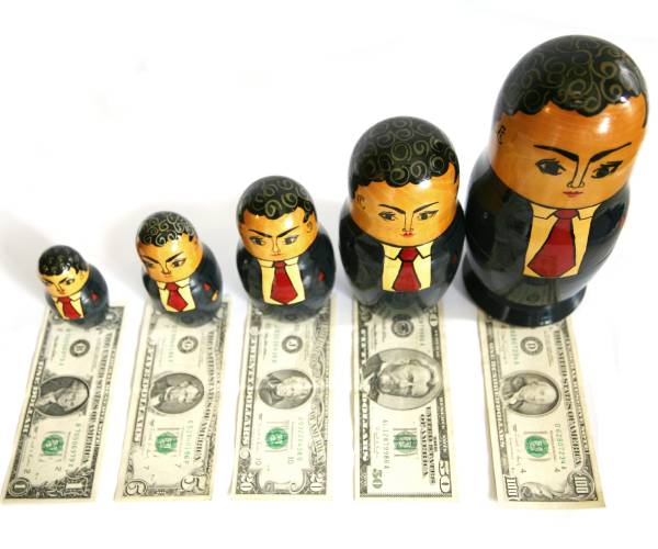 russian nesting dolls painted as businessmen with american money in front of them