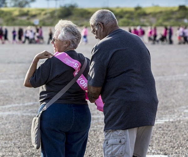 man helps woman put on sash