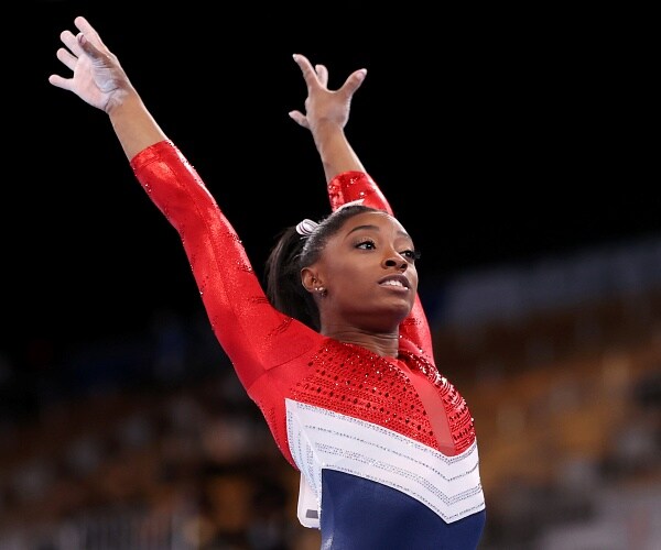 simone biles holds arms over head after landing vault