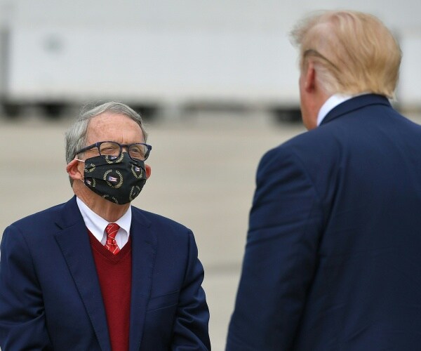 wearing a mask, mike dewine speaks to president trump on a tarmac
