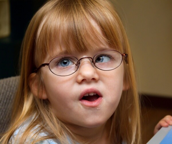 young girl with crossed eyes and corrective glasses