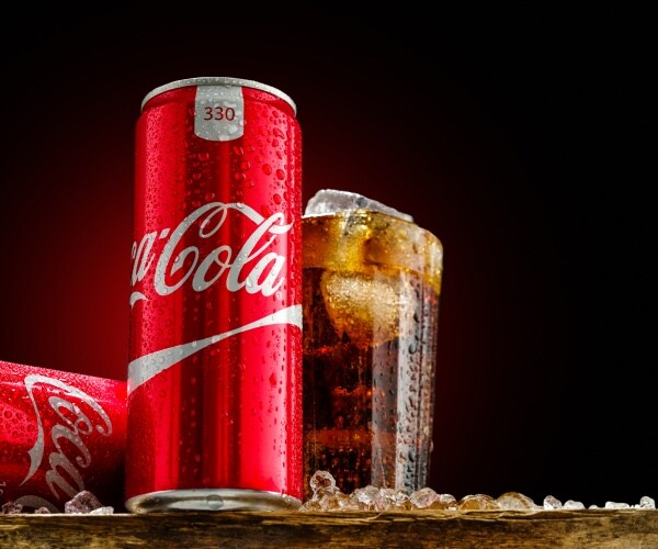 can and glass of coca cola with ice on wooden background