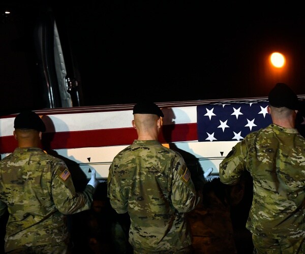 a military coffin being carried by service members